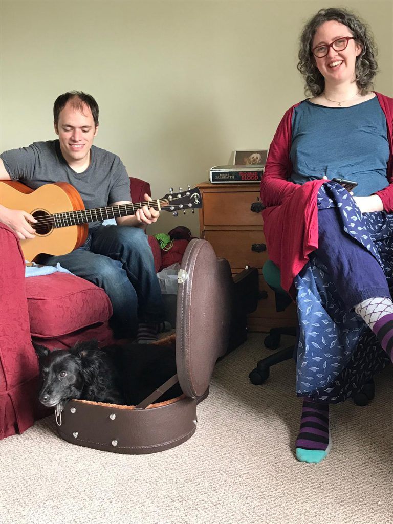 Francis and me smiling while Francis plays guitar, and Lilo (our dog) is curled up inside the guitar case